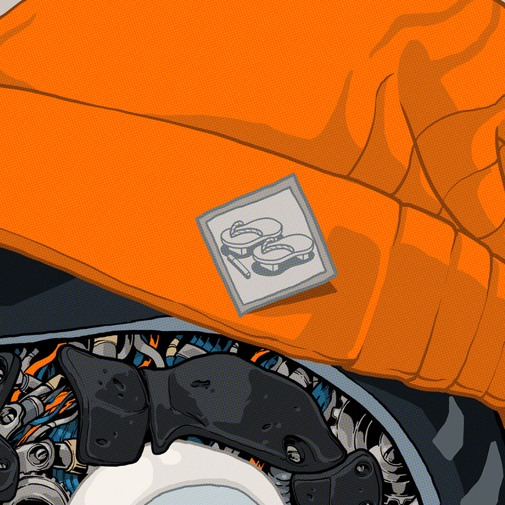 Close-up of an orange beanie with a patch showing shoes on a mechanical Daruma doll.